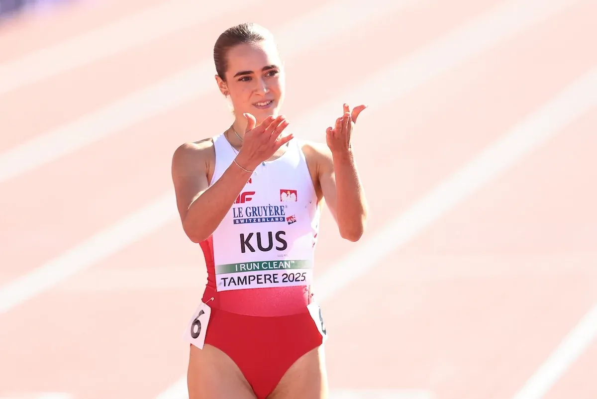 Lekkoatletka w stroju reprezentacyjnym Polski na stadionie podczas zawodów, klaszcze w dłoniach, wyraża radość lub uznanie.